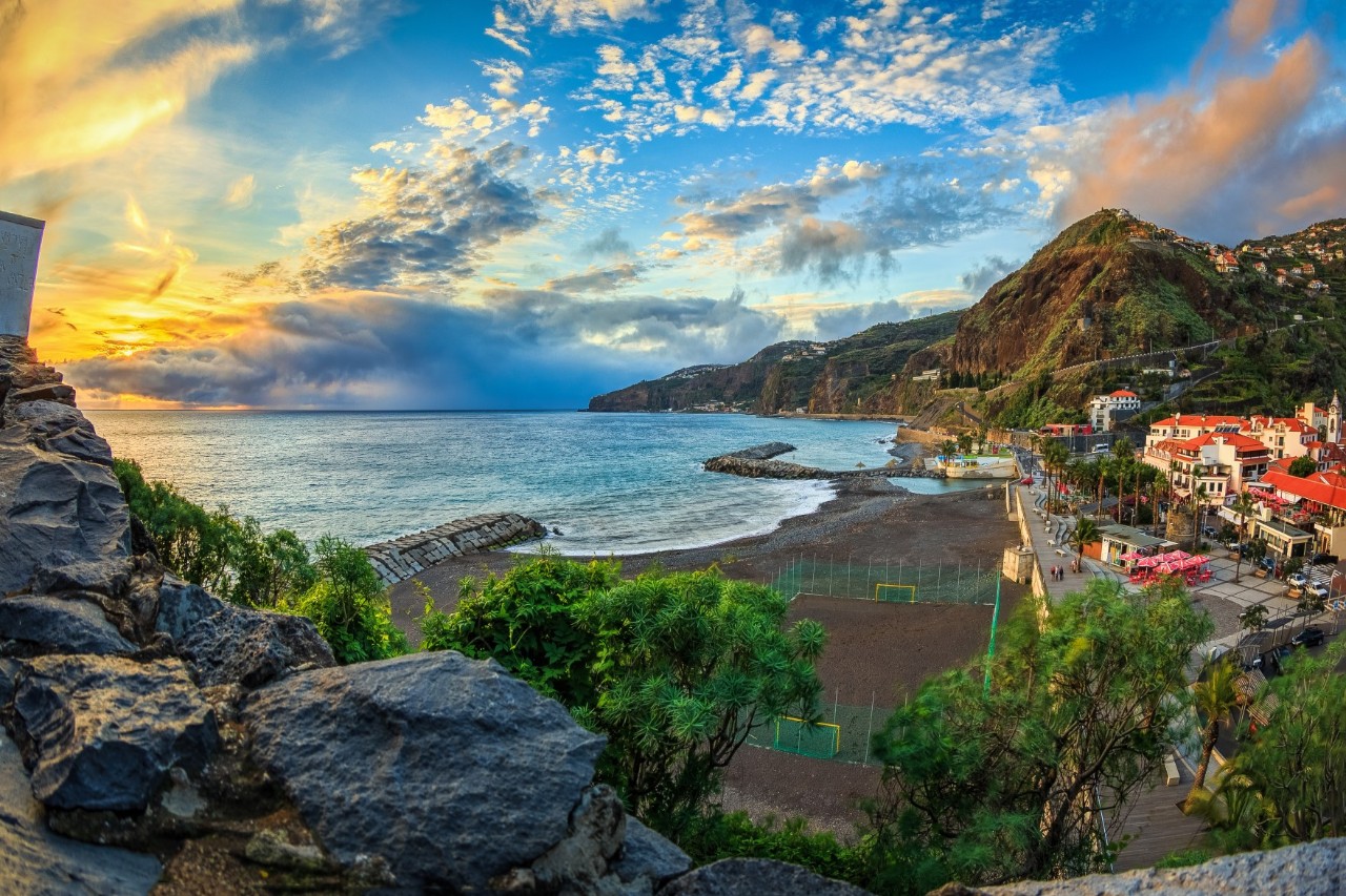 Sunset on a black beach of volcanic origin, with the town of Ribeira on the right and the mountainous coast in the background © papics/stock.adobe.com 