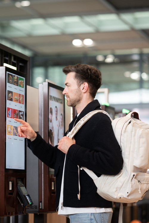 Ein Passagier gibt an einem Touchscreen im Food Court eine Bestellung auf.