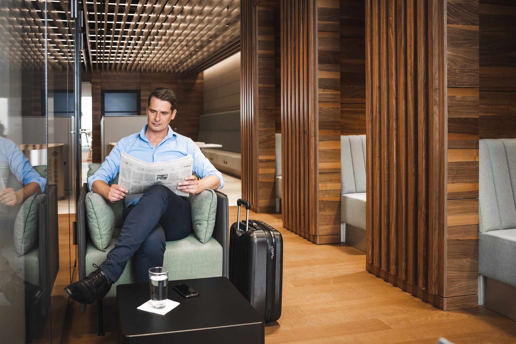 Man reads newspaper in lounge.