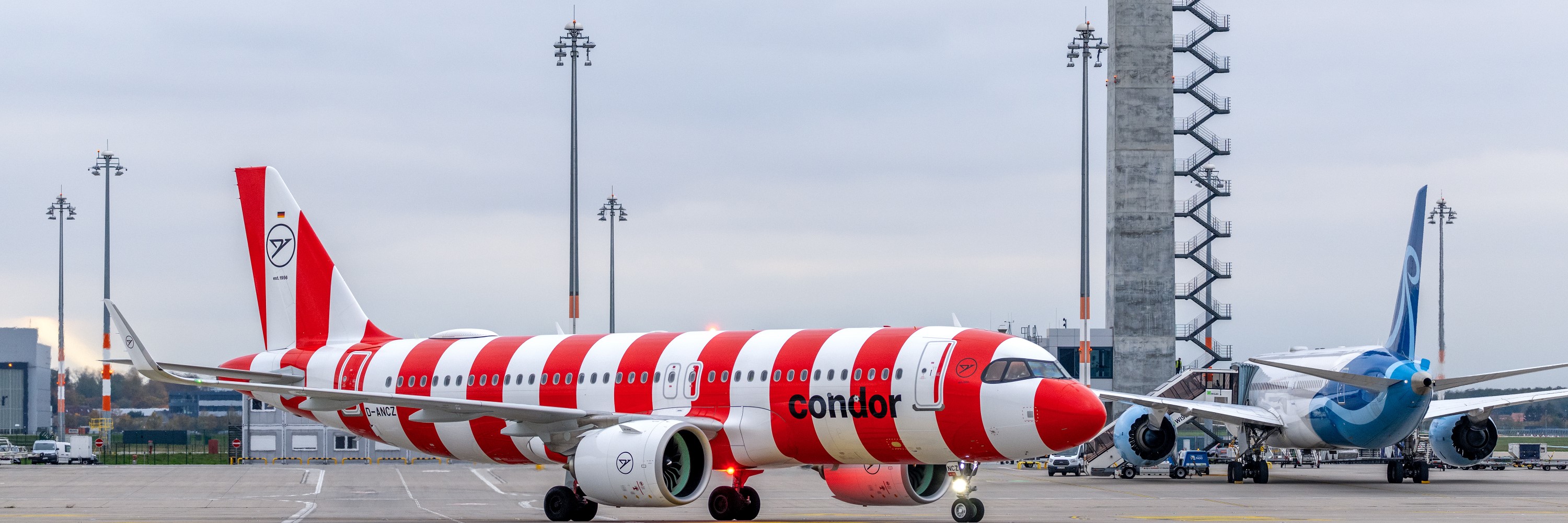 Red and white striped Condor aircraft. Behind it the tower.