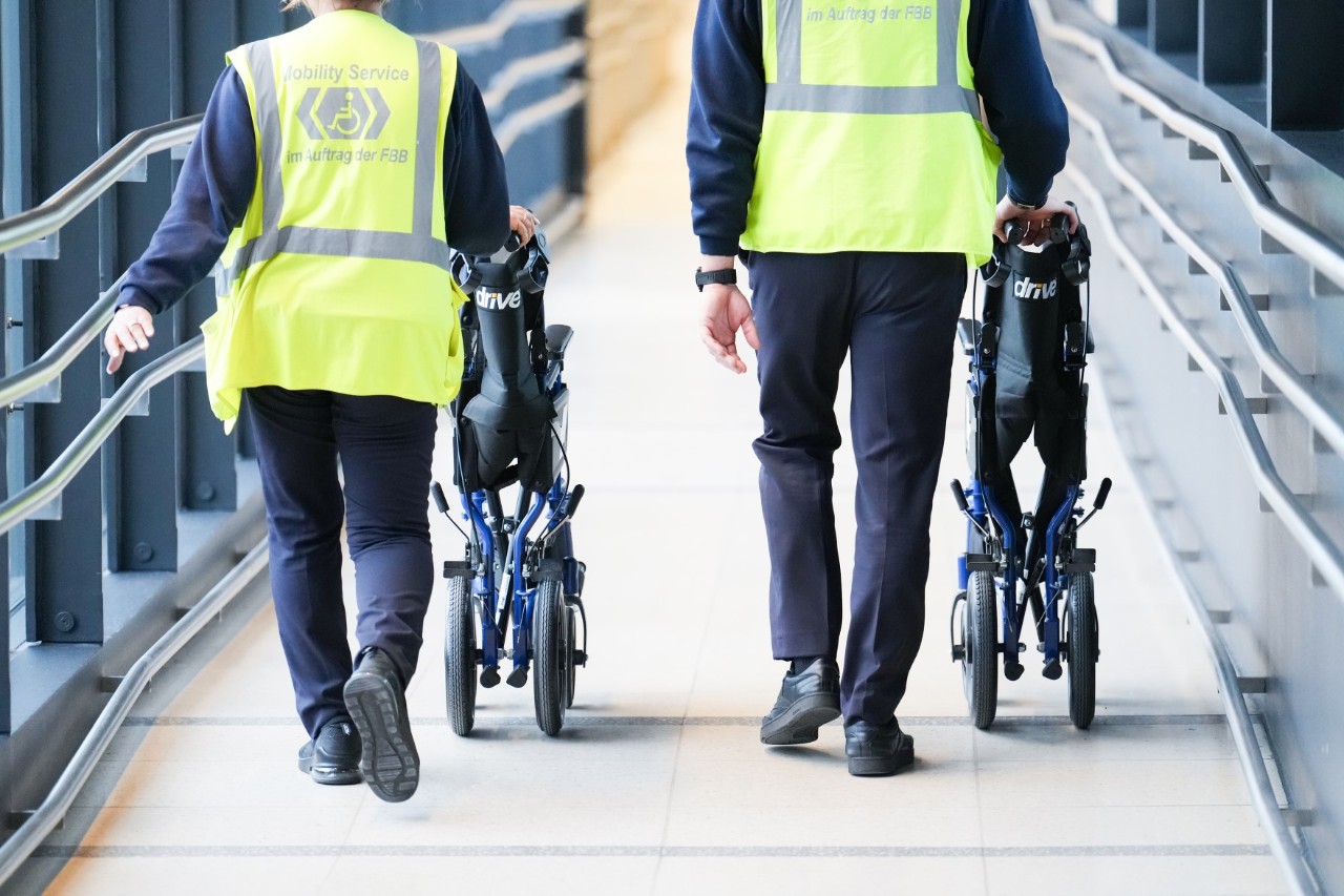 2 Mitarbeiter des Mobility Service schieben Rollstühle