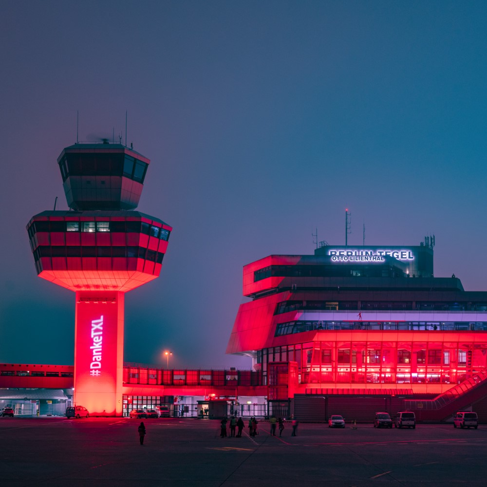 Rot beleuchteter Tower und rot beleuchtetes Terminal in Tegel. Dunkle Nacht.