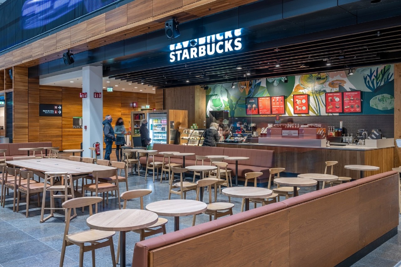 Blick auf den Tresen des Starbucks. Davor Stühle und Tische.