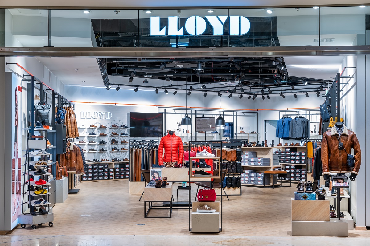 Blick von außen in den Laden LLOYD. Zu sehen Schuhe in den Wandregalen sowie Bekleidung in Aufstellern.