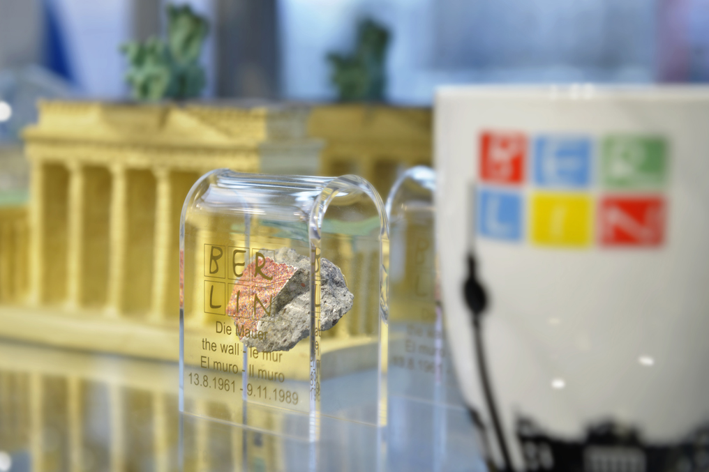 Detailaufnahme einer Tasse und eines kleinen Teils der Berliner Mauer.