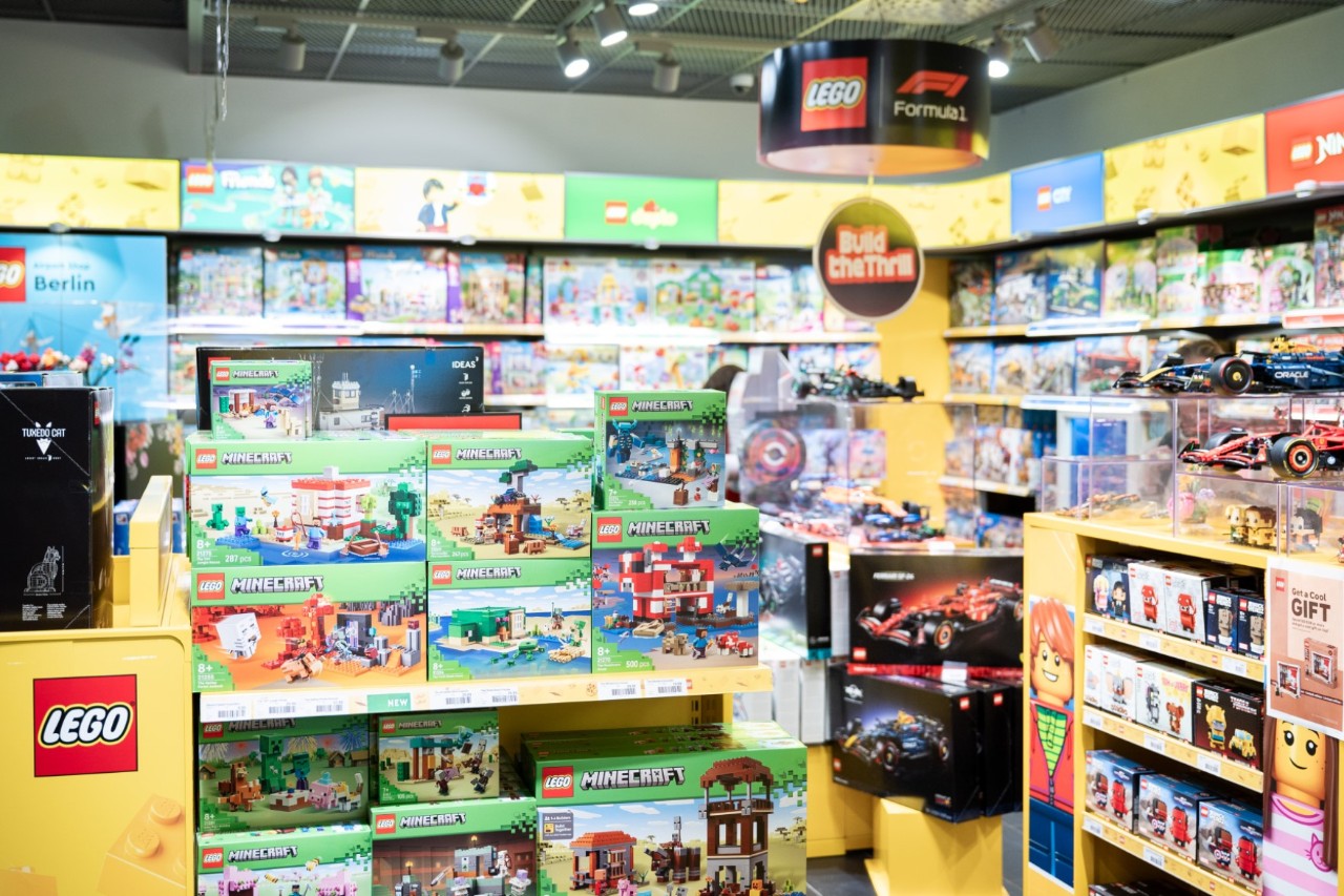 Innenansicht des LEGO Stores im Flughafen Berlin Brandenburg mit bunten LEGO-Sets in Regalen und auf einem Präsentationstisch.
