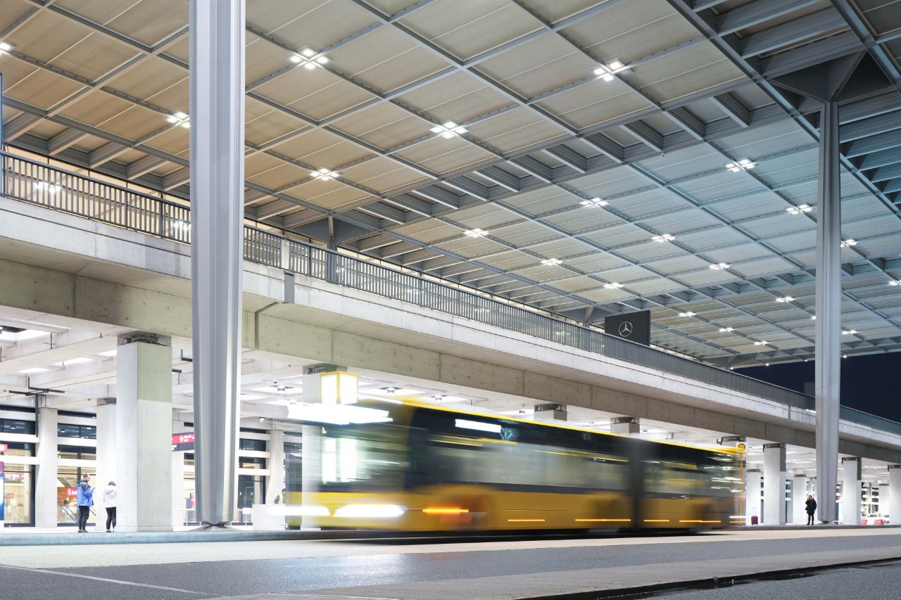 Ein gelber Bus vor dem Terminal 1 an der Bushaltestelle A.