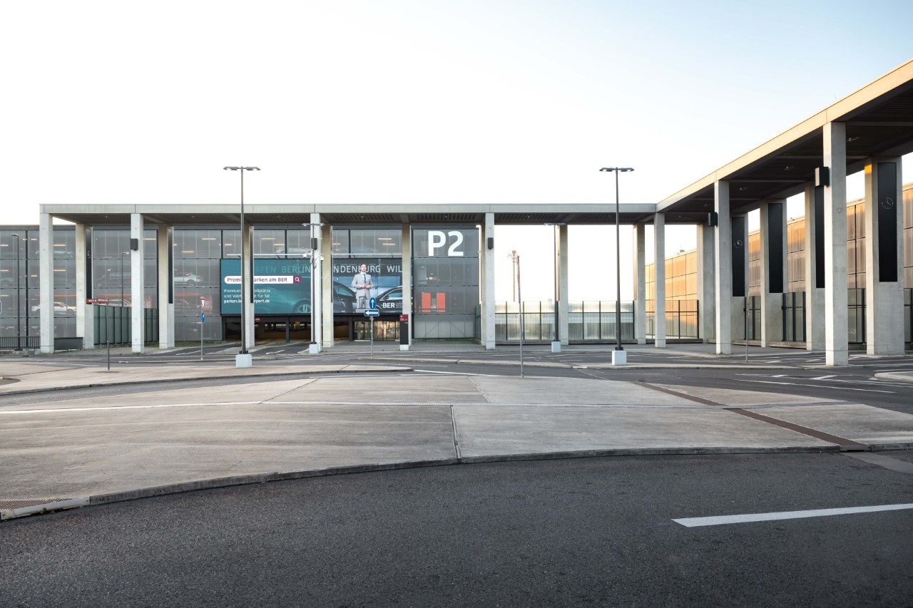 Das graue Parkhaus P2. Davor Autos.