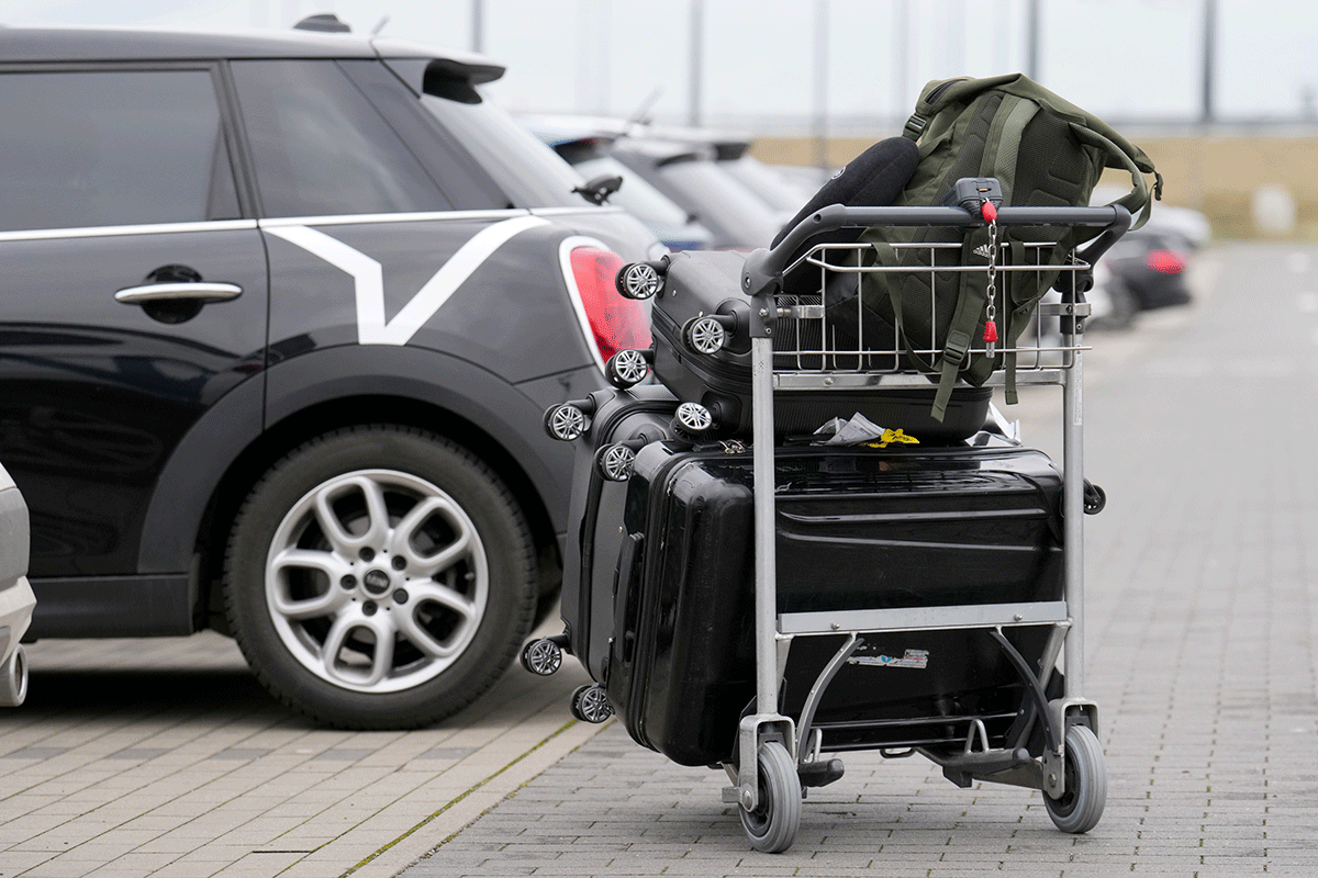 Parkplatz P4. Mehrere Autos. Davor ein Kofferwagen.