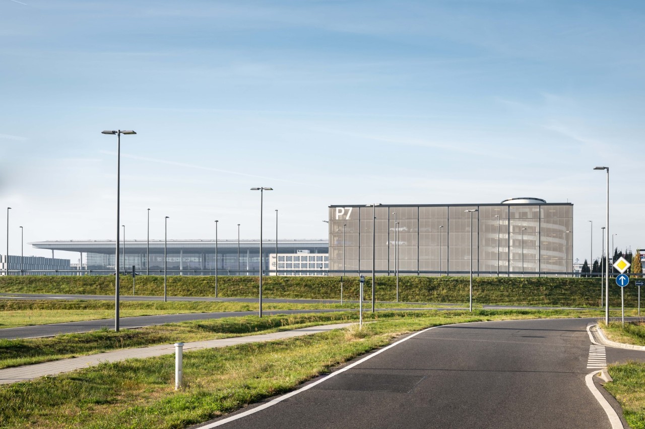 Im Vordergrund Wiese und Bäume. Im Hintergrund das Parkhaus P7.