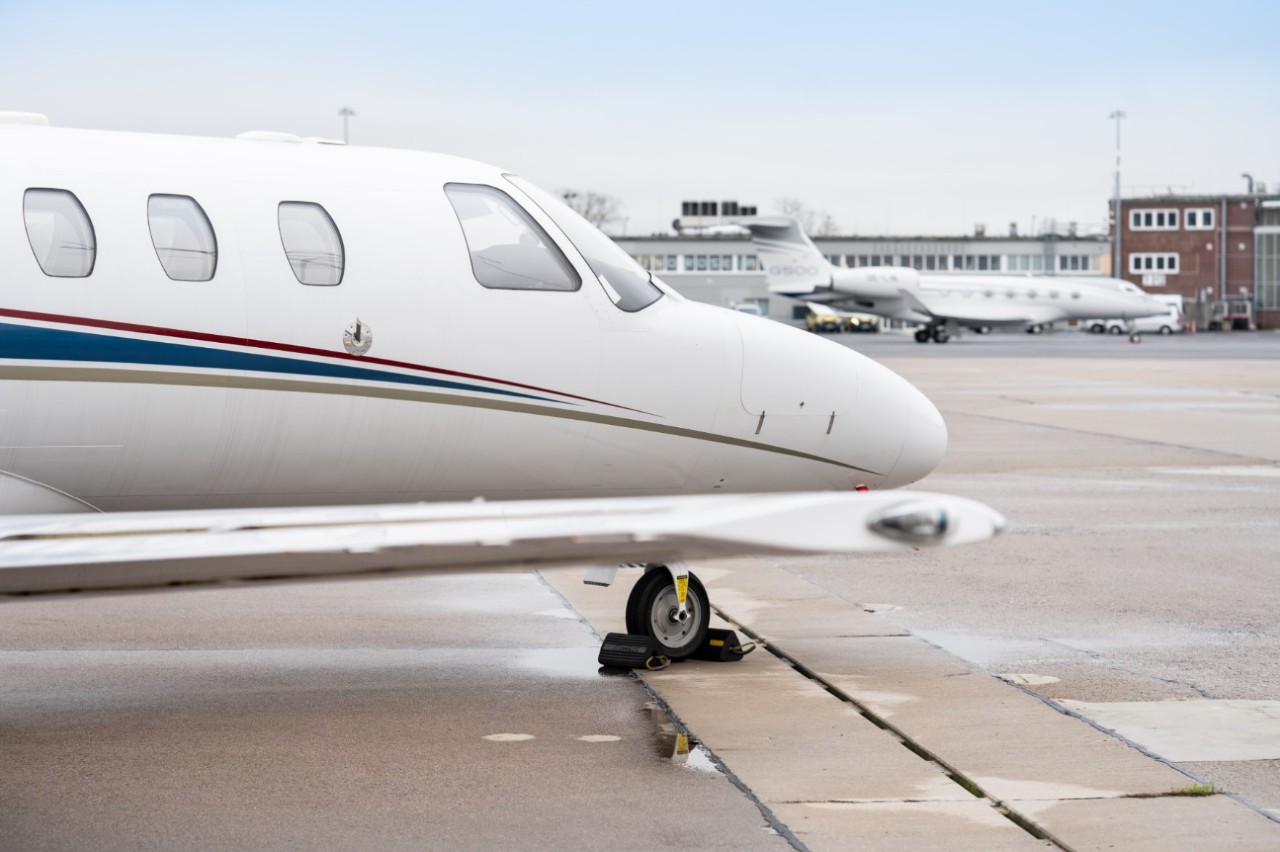 Geschäftsflugzeug auf Vorfeld. Dahinter ein Hangar.