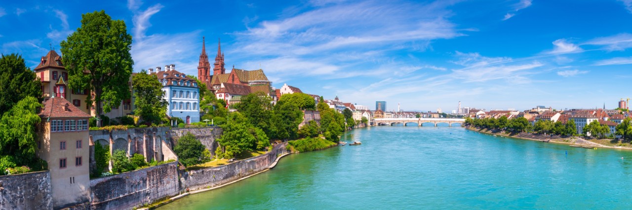 Blick den blaugrünen Fluss Rhein und die linksseitige Altstadt von Basel mit dem roten Münster © gatsi/stock.adobe.com