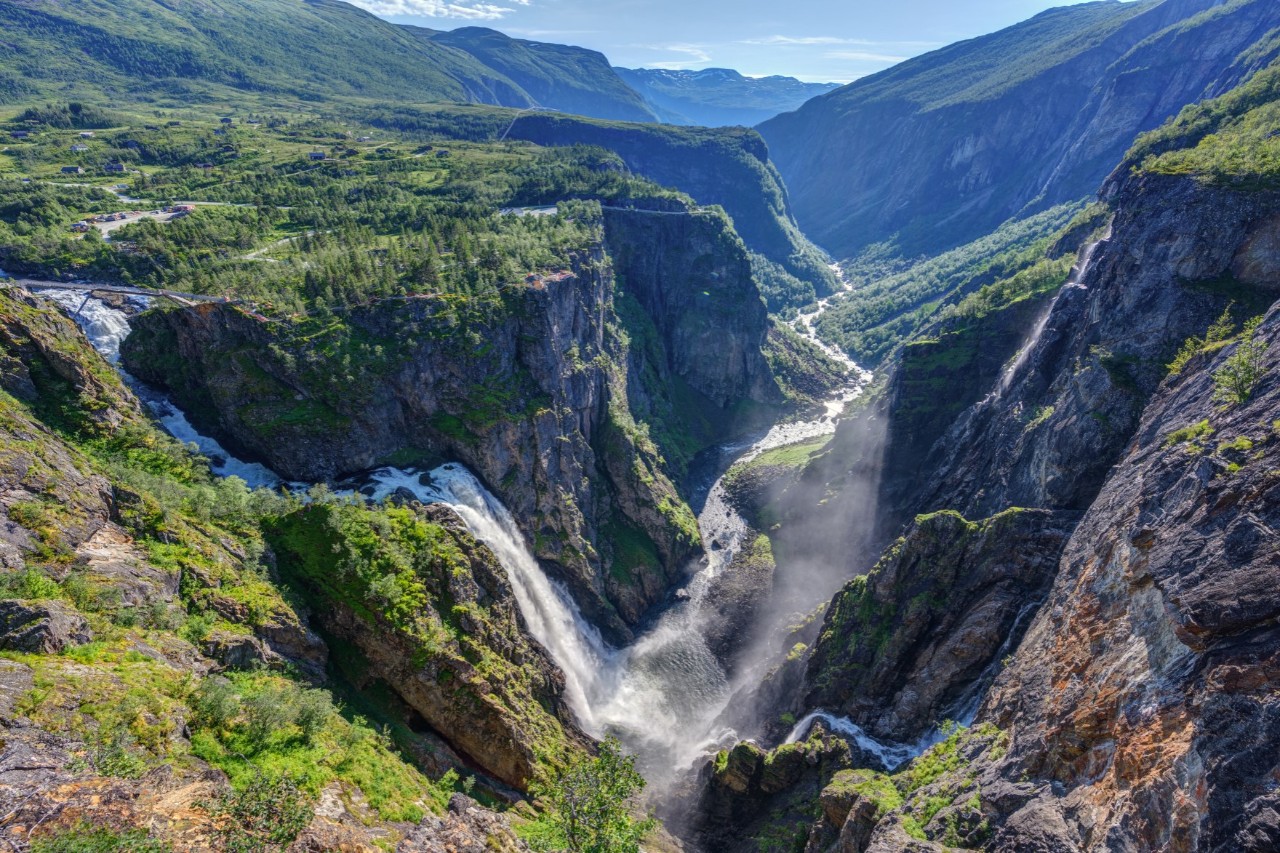 Vøringfossen stürzt in tiefe Schlucht mit Felsen und grüner Vegetation.