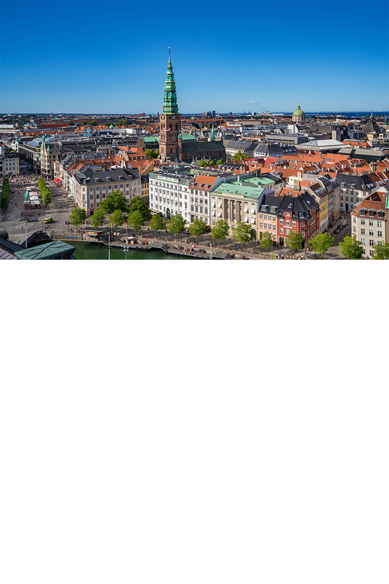 Altstadt von Kopenhagen. Kirchen ragen heraus. Dahinter das Meer.