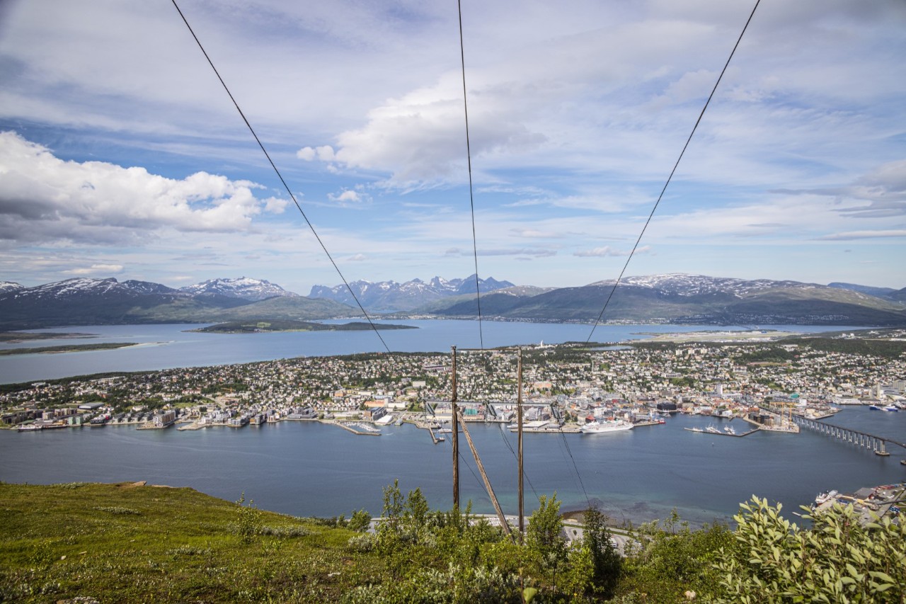 Ausblick auf Tromsø vom Berg mit Seilbahnkabeln im Vordergrund.