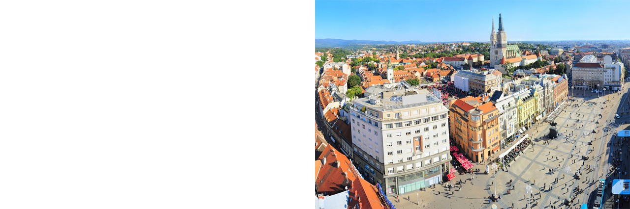 Blick auf eine große, belebte Einkaufsstraße, rundherum viele Häuser, im Hintergrund ist eine Kirche. © joyt/stock.adobe.com  