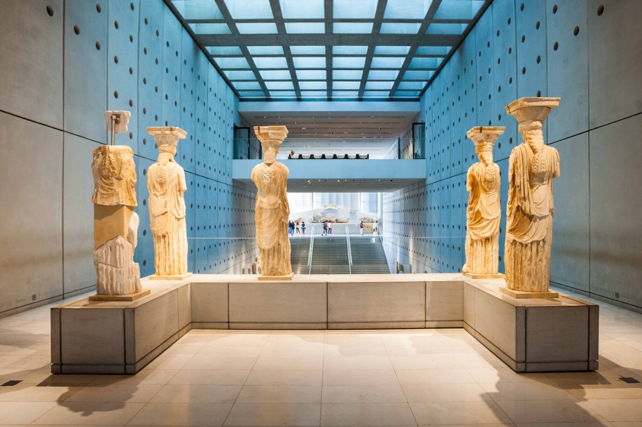 Antike Statuen im Akropolis Museum vor neutralem Hintergrund.