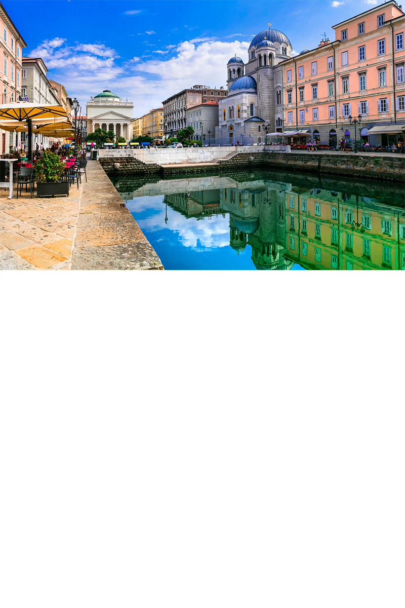 Blick auf die Innenstadt von Triest: Elegante Häuser und Paläste entlang eines Kanals, in dem sie sich spiegeln, Straßencafé mit Sonnenschirmen und Pflanzen. © Freesurf/stock.adobe.com  
