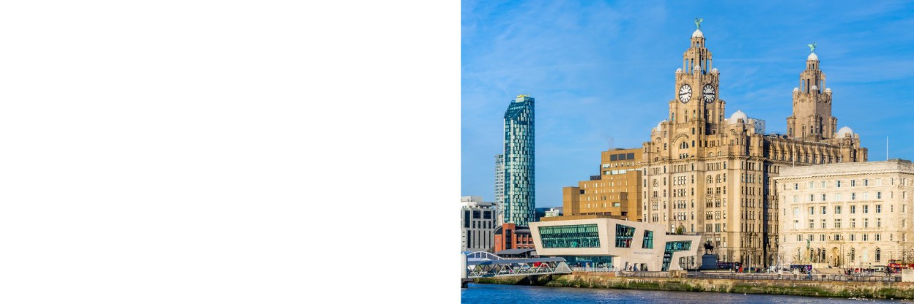 Das Bild zeigt eine Uferpromenade mit historischen Gebäuden, wie das Royal Liver Building mit zwei Türmen sowie klassische und moderne Häuser, darunter ein Hochhaus. 