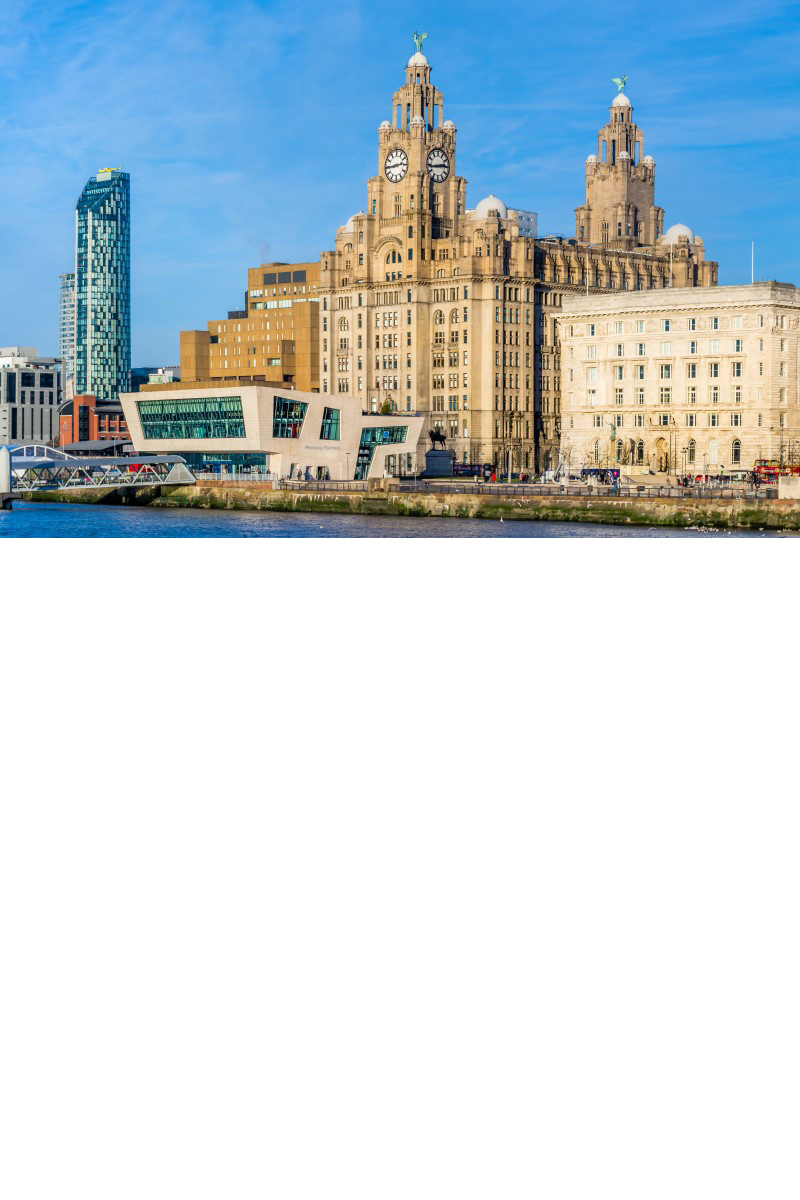 Das Bild zeigt eine Uferpromenade mit historischen Gebäuden, wie das Royal Liver Building mit zwei Türmen sowie klassische und moderne Häuser, darunter ein Hochhaus. 