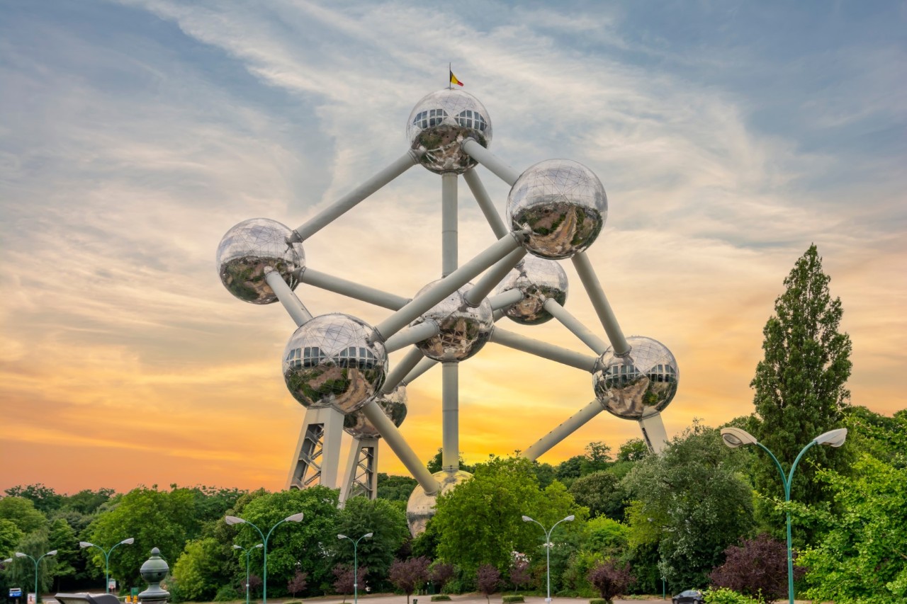 Wahrzeichen Atomium, Gerüst aus neun Kugeln, grüne Bäume, gelb verfärbter Himmel 