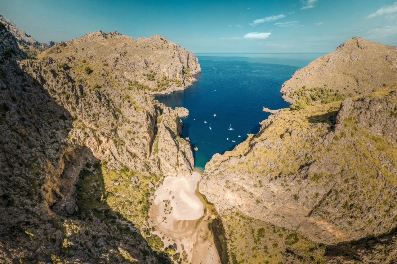 Luftbild der Schlucht Sa Calobra auf Mallorca, das Meer ragt in die Schlucht, darauf sind mehrere Boote zu sehen © Jonas Weinitschke/stock.adobe.com
