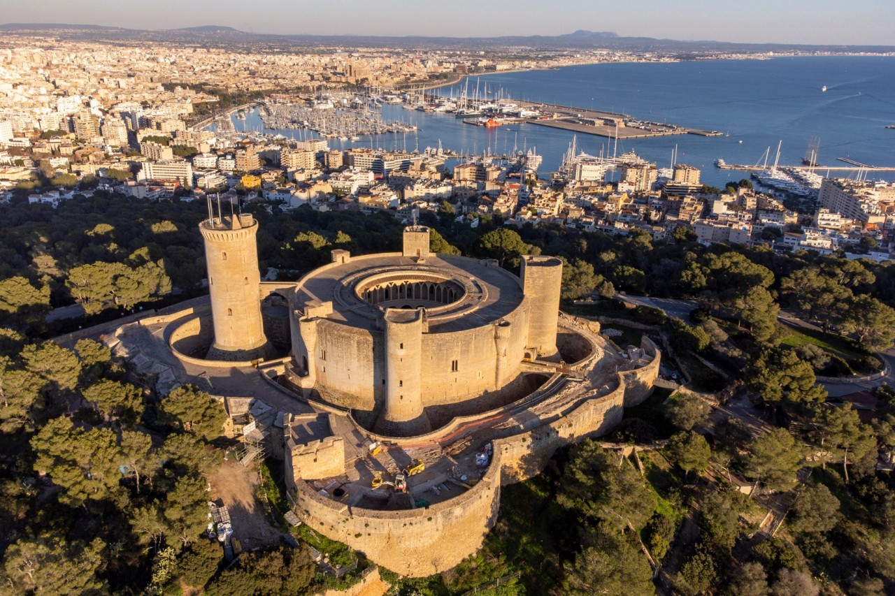 Luftbild der Festung Castell de Bellver in Mallorcas Hauptstadt Palma mit Häusern und dem Hafen im Hintergrund