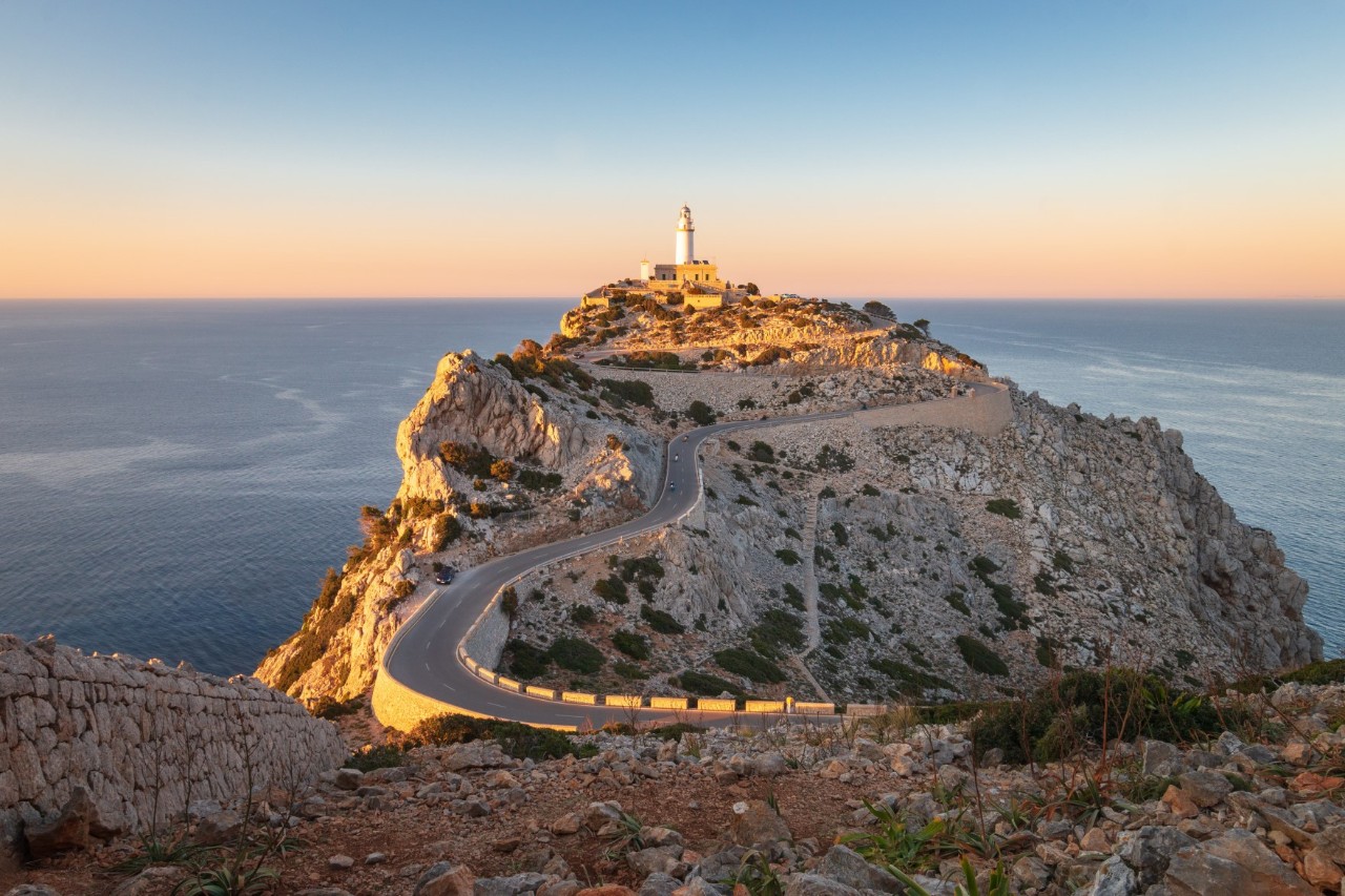 Straße zum Cap de Formentor auf Mallorca mit einem Leuchtturm auf der Klippe und Meereshintergrund in der Abendsonne 