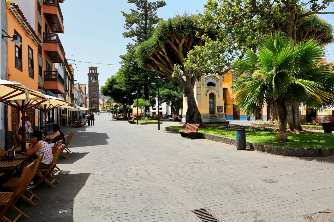 Ruhige Fußgängerzone in La Laguna mit Menschen in Straßencafés, farbenfrohen Häusern und Bäumen © Argus/stock.adobe.com