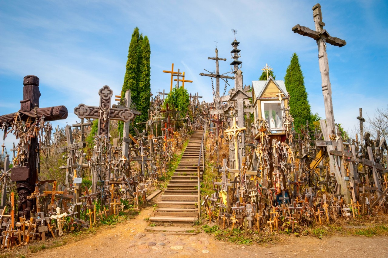 Holztreppe, die auf einen Hügel führt, der voller kleiner und großer christlicher Kreuze ist 