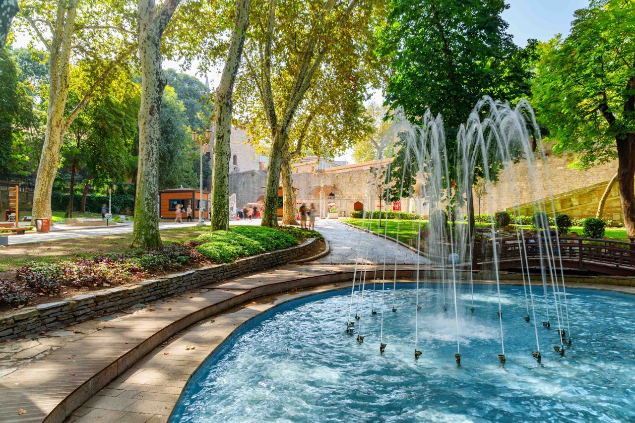 Springbrunnen im Gülhane-Park umgeben von Blumen und Bäumen.