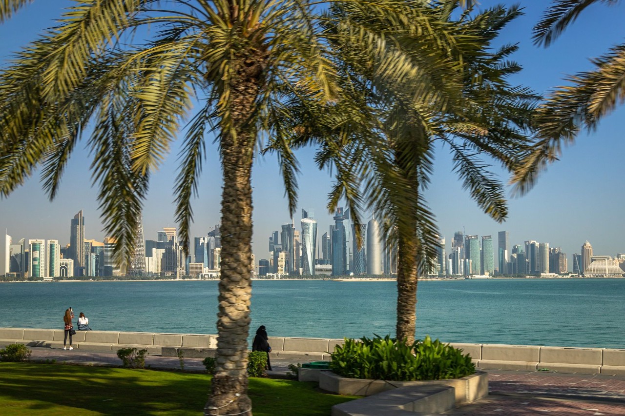 Die Uferpromenade von Katar. Palmen am Meer. Im Hintergrund die Skyline.