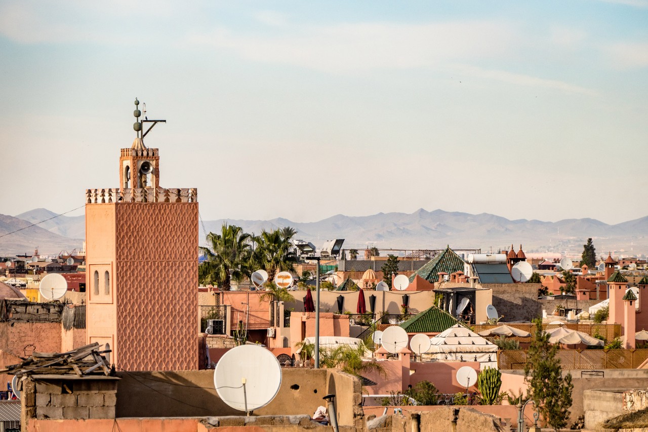 Rote Lehmhäuser und Festungsmauer in Marrakeschs Medina bei Sonnenschein.