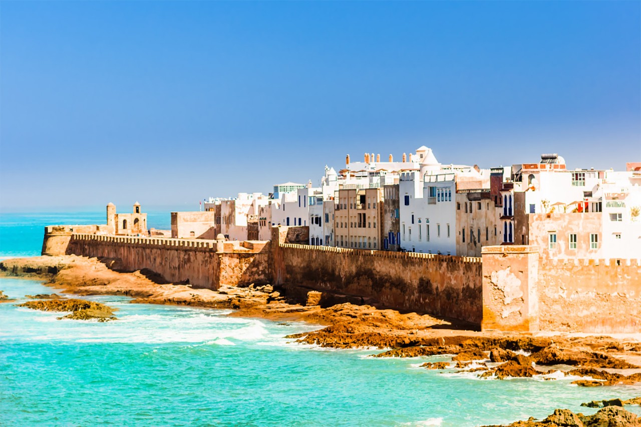 Hafen von Essaouira mit Booten und Stadtmauer bei sonnigem Wetter.