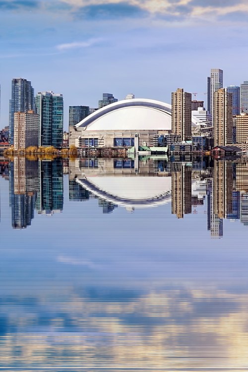 Skyline einer großen Stadt mit Hochhäusern, die sich in einer glatten Wasserfläche spiegeln.