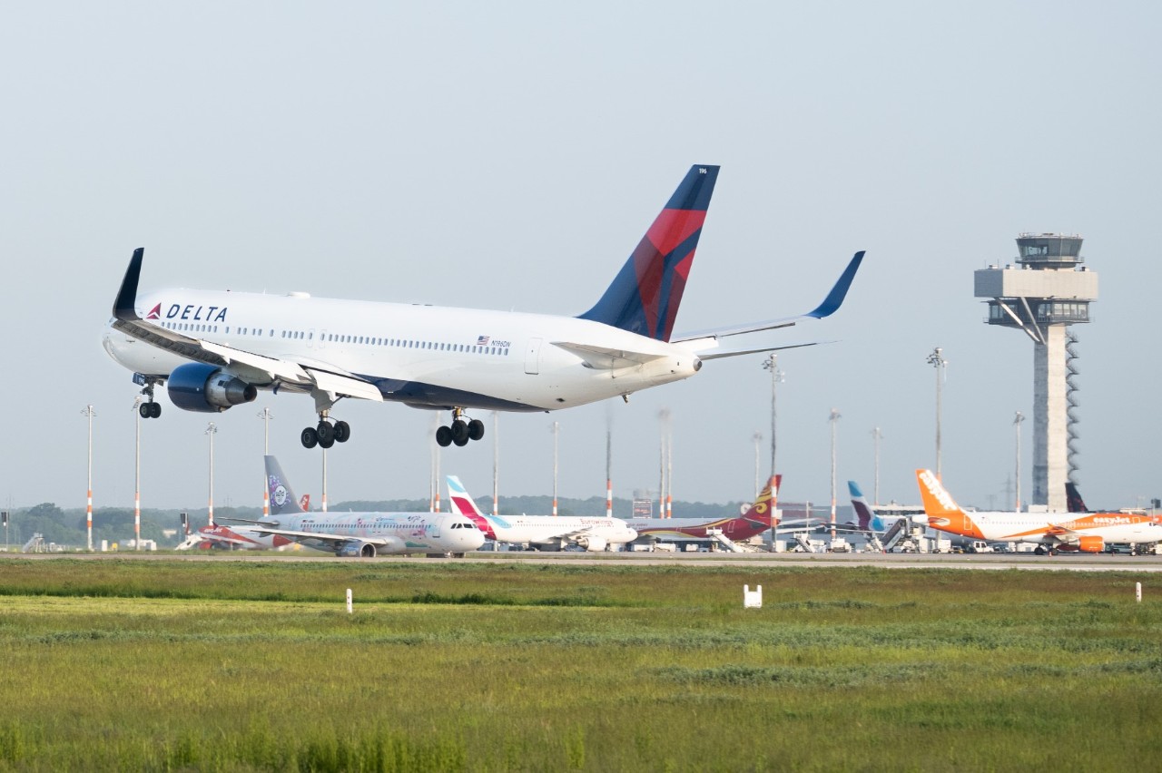 Delta Airlines landet am BER. Im Hintergrund Flugzeuge und Tower.
