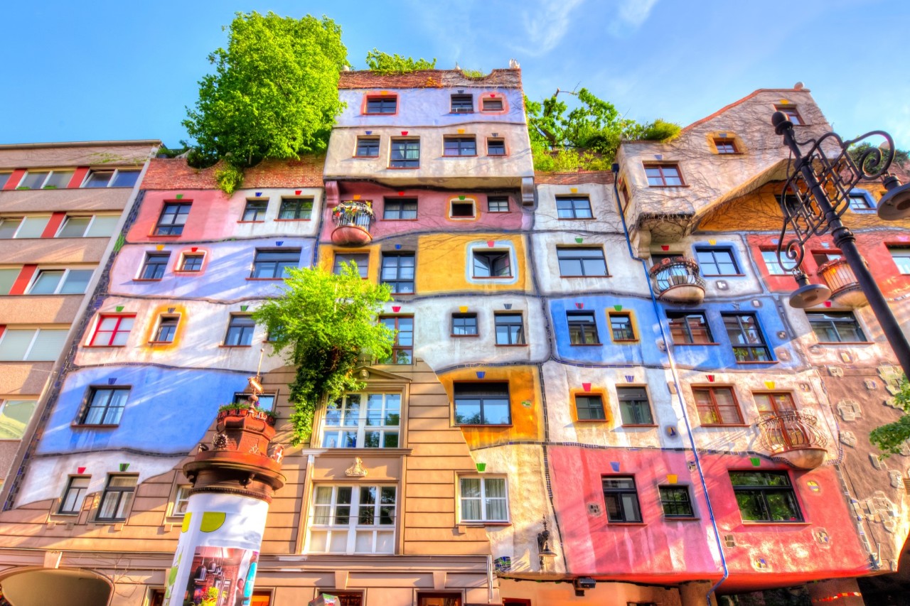 Buntes Hundertwasserhaus mit begrüntem Dach.