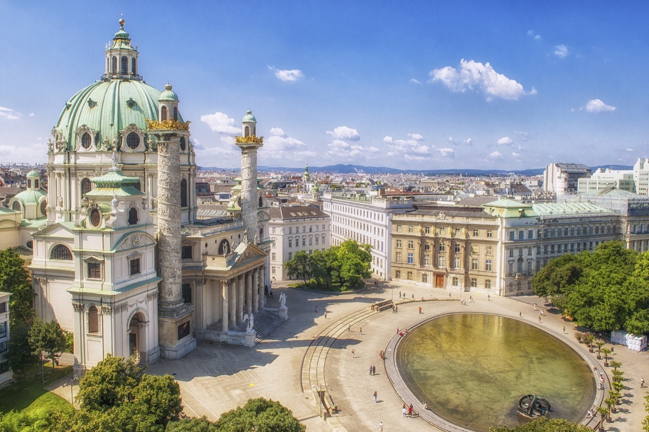 Karlskirche mit Kuppel und Spiegelteich bei Sonnenschein.