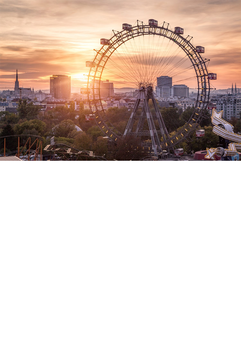 Riesenrad in Wien bei Sonnenuntergang mit Skyline im Hintergrund.
