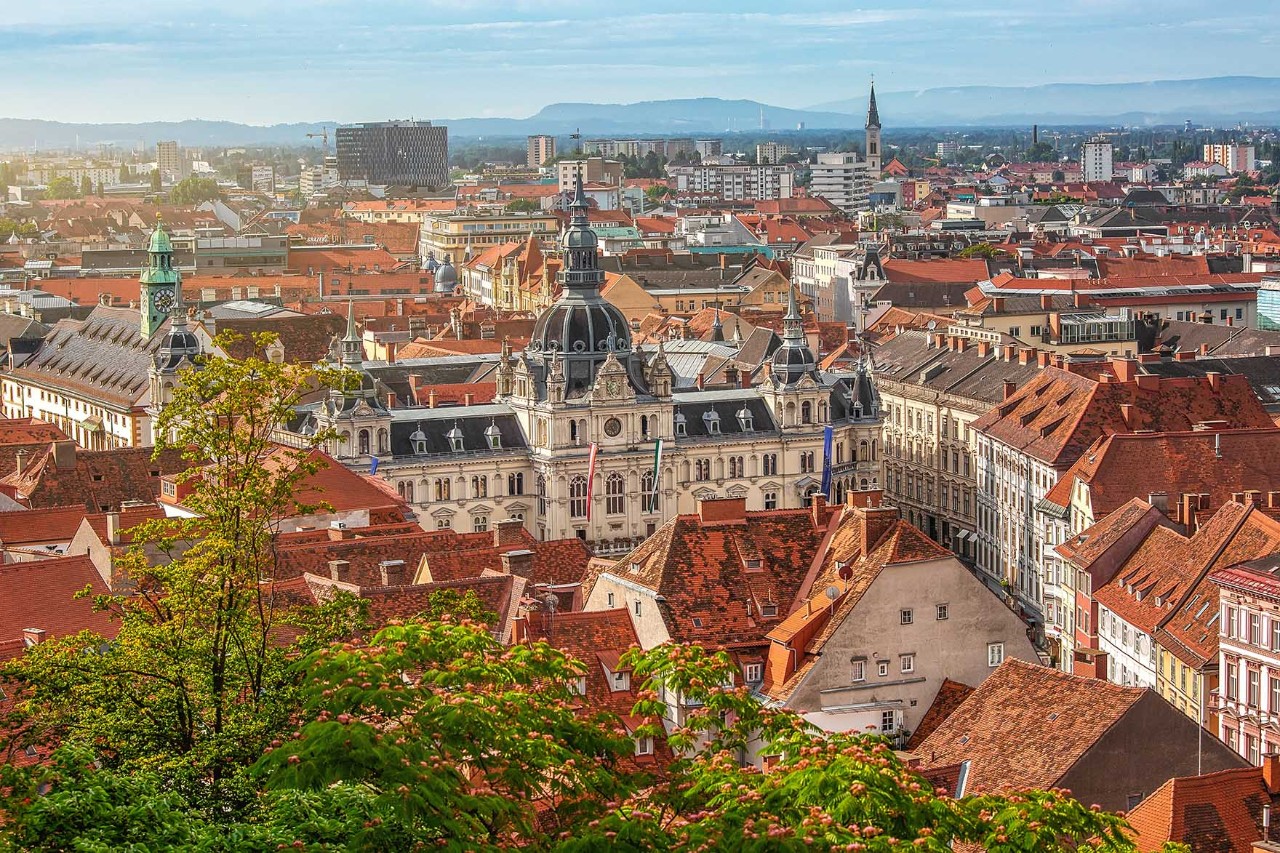 Luftbild von Graz mit rotem Ziegeldachmeer und grünem Schlossberg.
