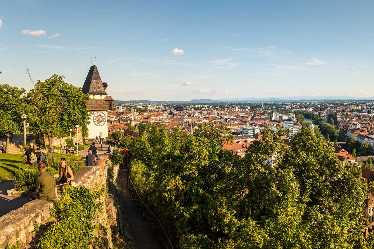 Schlossberg in Graz mit Uhrturm, umgeben von Bäumen und alten Mauern.