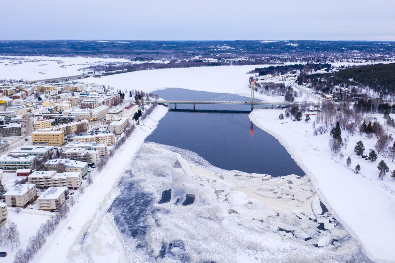 Luftbild von verschneiter Stadt an einem zugefrorenen Fluss mit Brücke.