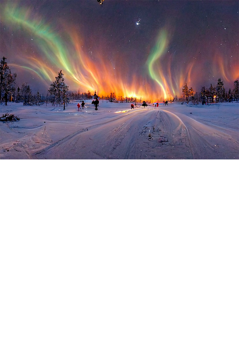 Blick auf Polarlichter über verschneiter Winterlandschaft mit Menschen im Schnee.