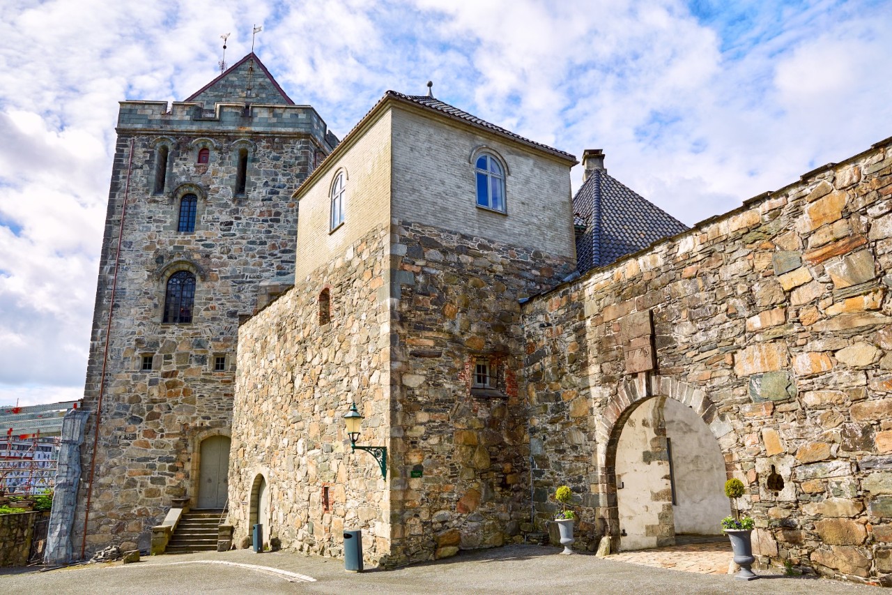 Alte Steinmauern der Bergenhus Festung mit Turm und Rasenfläche.