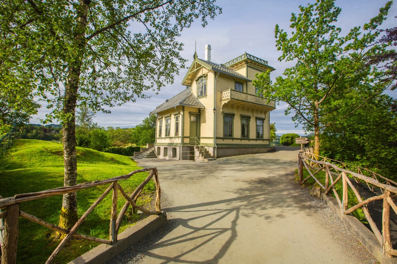 Edvard Griegs Villa Troldhaugen mit Garten und Bäumen im Hintergrund.