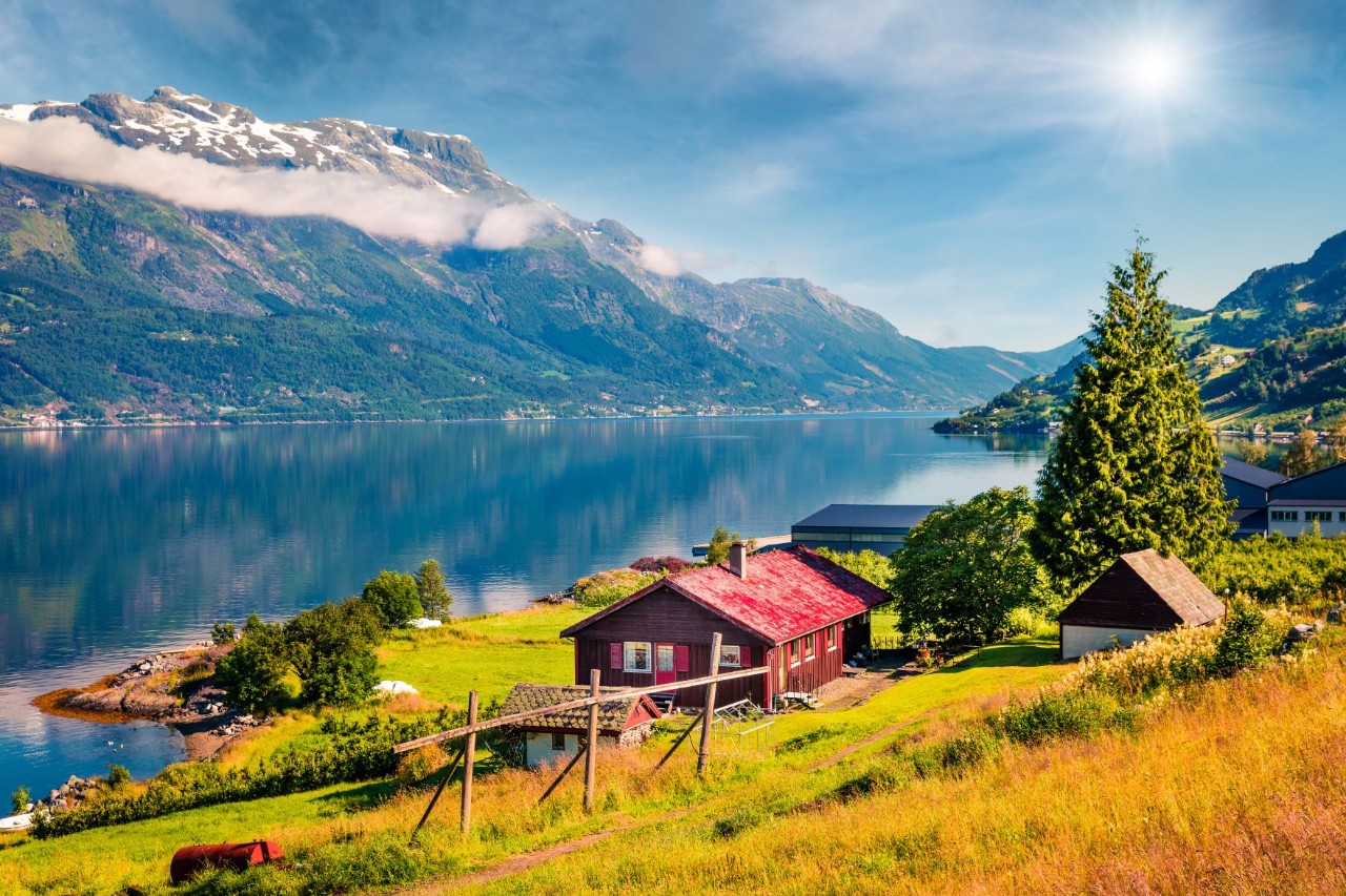 Bauernhof am Hardangerfjord mit Obstbäumen und Bergen im Hintergrund.