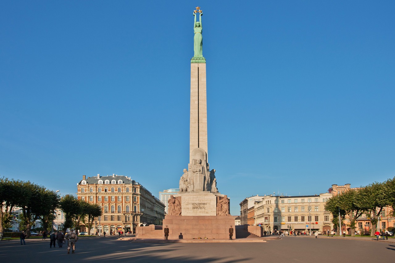 Freiheitsdenkmal mit bronzener Statue und grünem Sockel vor blauem Himmel.