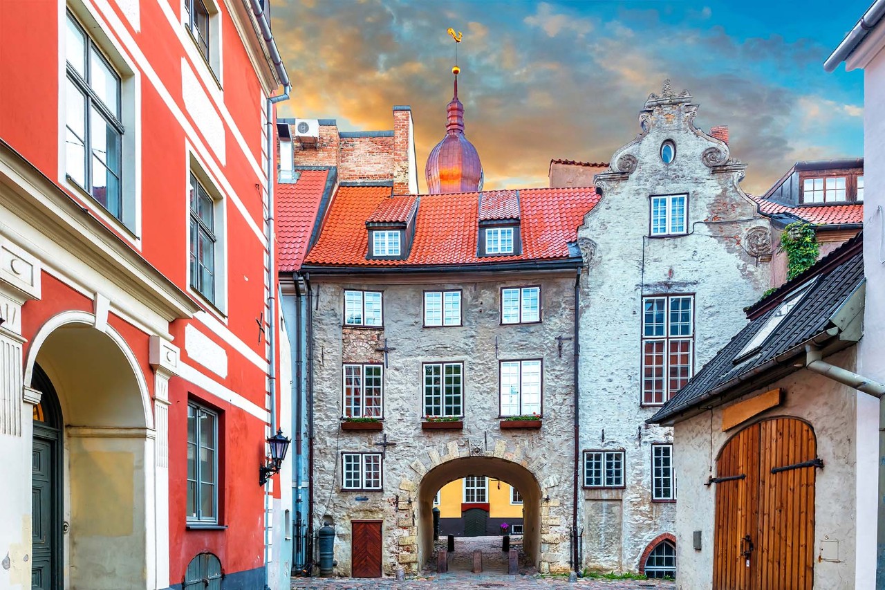 Historische Altstadtgasse mit Kopfsteinpflaster und bunten Gebäuden bei Sonne.