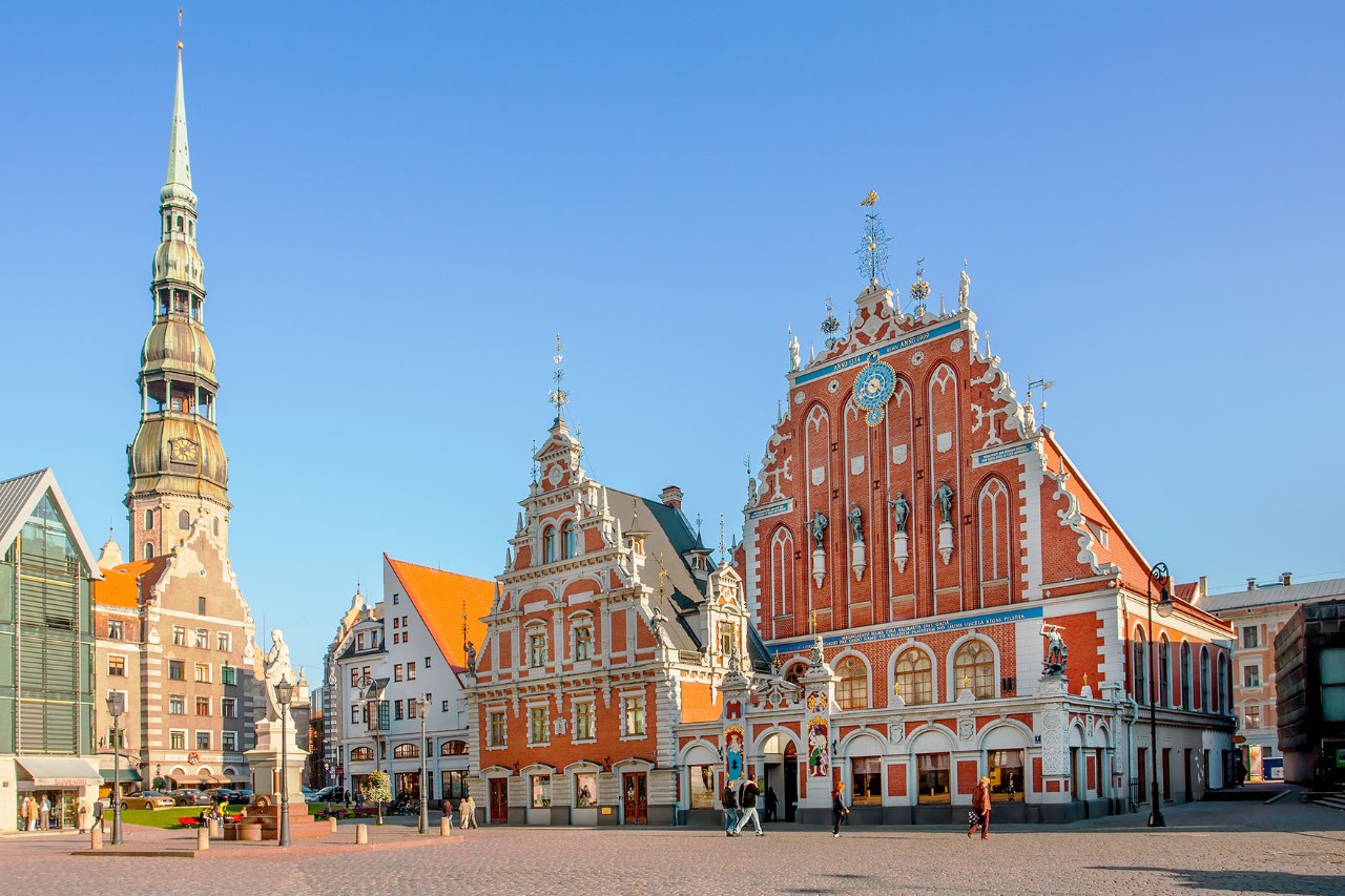 Altstadt von Riga mit bunten Häusern und Kirchturm bei Tageslicht.