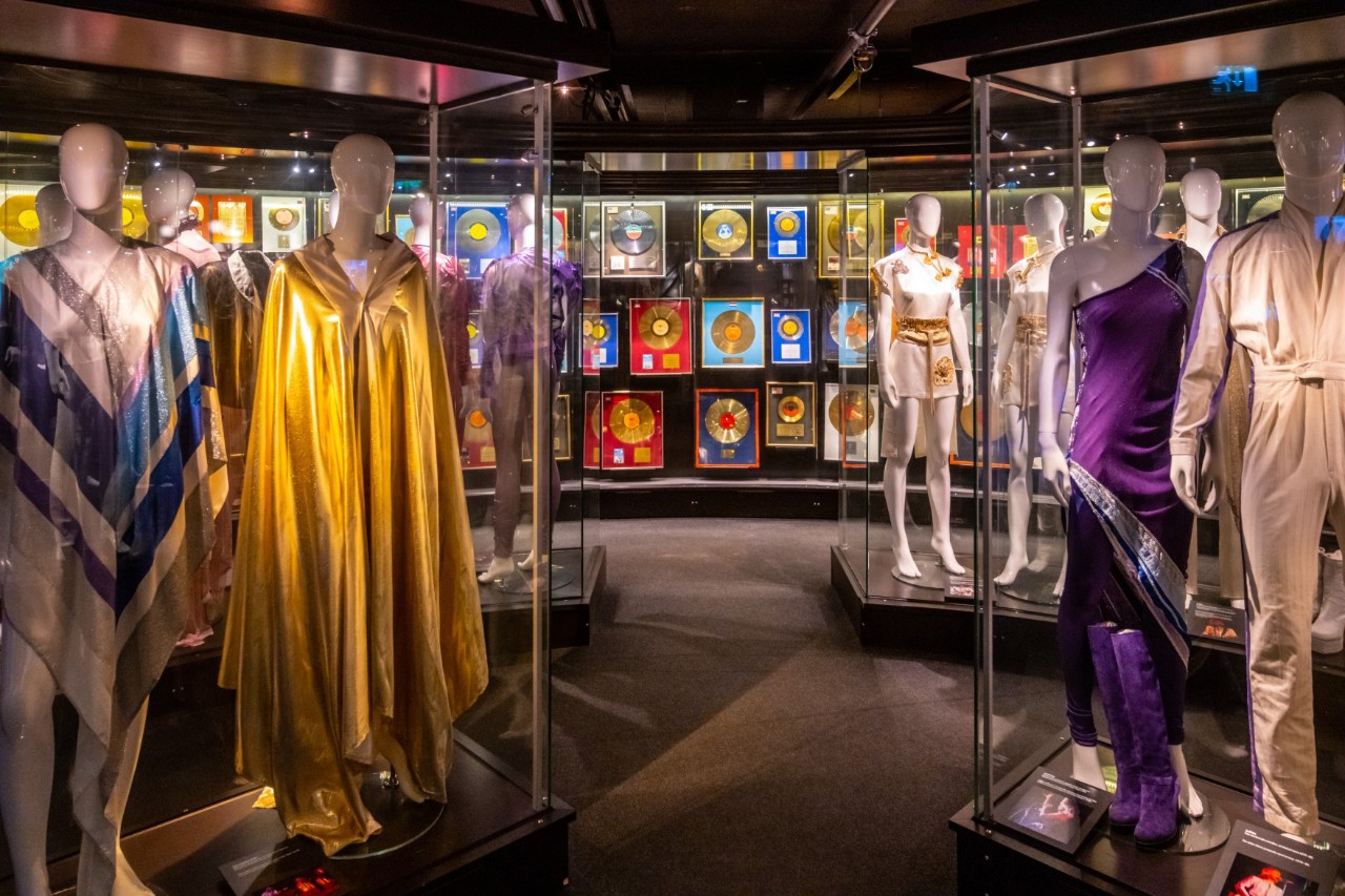 Innenansicht des ABBA-Museums mit Kostümen und goldenen Schallplatten in Vitrinen.